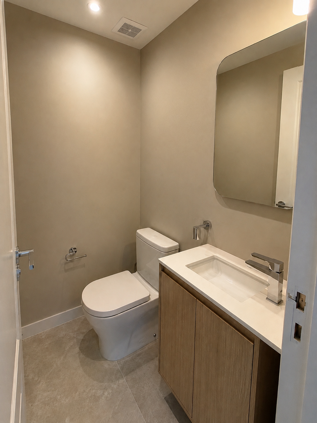 Baño revestido en tonos piedra con ducha de vidrio